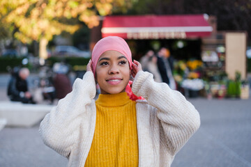 Young woman with cancer putting on the pink cap to fight for the disease and as a symbol. Concept:...