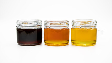 Jars with three different types of honey isolated on a white background