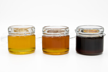 Jars with three different types of honey isolated on a white background
