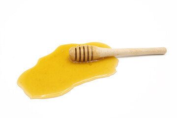 Honey dipper on spilled honey isolated on white background