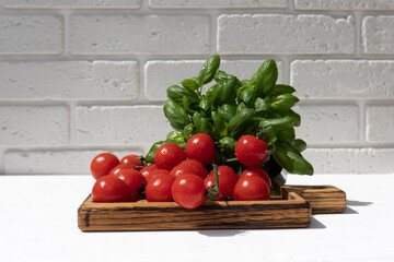 Healthy food background. A fresh vegetables, tomatoes and green basilica on white wooden background with wooden tray