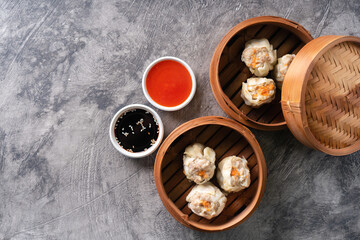 Chinese steamed dumplings or  Dim Sum in bamboo steamer on dark abstract background