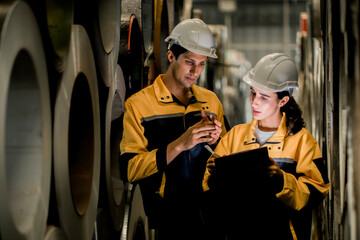 Two maintenance engineers men and women industrial factory behind she talking with workers. They...