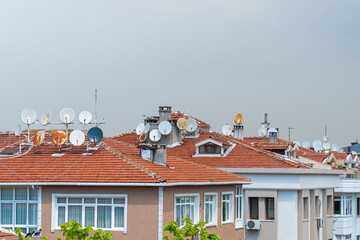 House rooftop with many satellite dishes and TV antennas