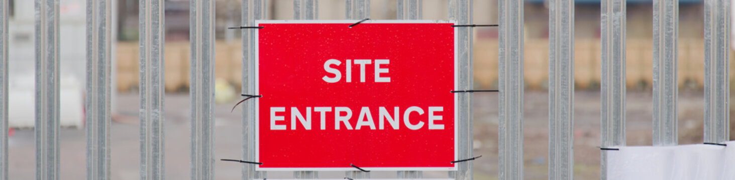 Site entrance sign on fence boundary at construction site