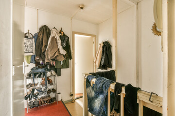 a room with clothes hanging on the wall and an open door that leads to another room in which is white