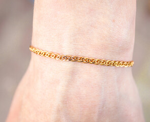 Gold chain of gold on the wrist of a woman, girl. Jewelry for a woman's hand, golden,...