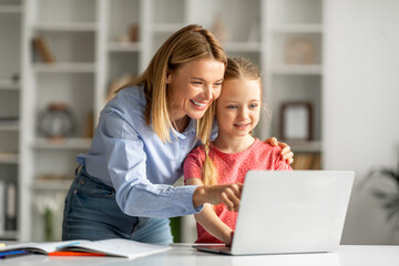 Loving Mom Helping Her Little Daughter To Study With Laptop At Home