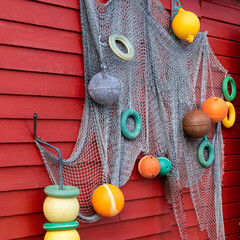 decoration of fishing net and colorful buoys on a red painted wooden house on the loftoen in norway