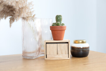 Indoor succulent plant in ceramic pot. Desk with stylish decoration at home, copy space. Modern interior workspace with cactus, vase with dried flowers, blank blocks wooden calendar. 