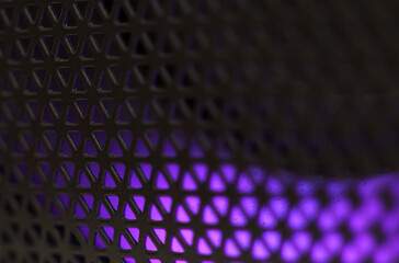 Abstract background of a black patterned lattice behind which blue LEDs glow