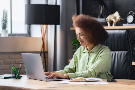 African American woman working using laptop while sitting in modern office