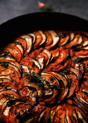 French ratatouille with tomatoes, eggplant, zucchini and fresh herbs in a cast iron skillet against...