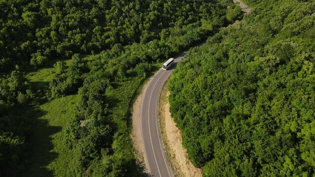 aerial view drone view on bus on the road trough the trees in mountain range in spring sunny day - Tresibaba Knjazevac in Serbia - Travel journey and vacation concept car driving