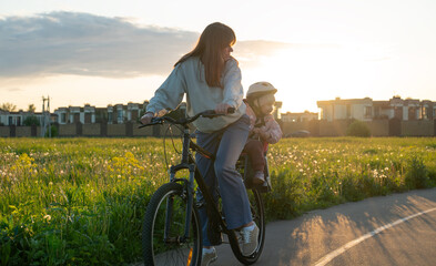 Woman with 3 year old girl on a bicycle in a countryside road