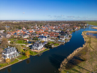 Aerial drone photo of luxury houses next to a river in Warmond