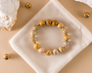 a bracelet made of petrified coral with gold round inserts to increase tone and relieve fatigue, reduces tension, fear, and gives prudence. beige background.