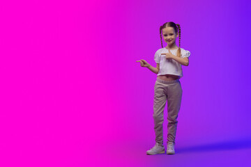 Fototapeta na wymiar Pretty little girl pointing at copy space, futuristic background