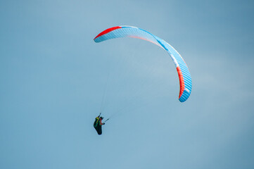 Paraglider flies in the air. Aerial view of paragliding. Paraglider flies in a bright sunny day. Concept of extreme sport.
