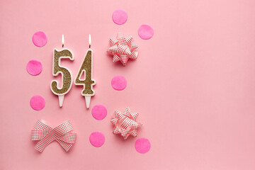 Number 54 on pastel pink background with festive decor. Happy birthday candles. The concept of celebrating a birthday, anniversary, important date, holiday. Copy space. Banner