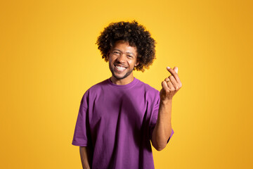 Glad confident mature black curly man in violet t-shirt snaps fingers gesture