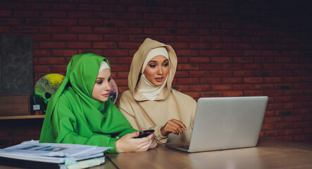 Young muslim asian female designer using graphics tablet while working with computer at studio or...