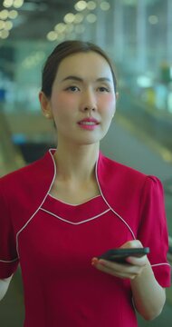 Air hostess using phone at escalator in airport. Asia woman commuter travels with luggage on escalator.