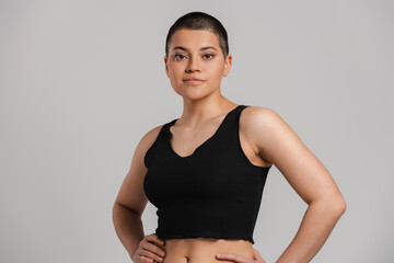 Beautiful young short hair woman in tank top looking at camera against grey background