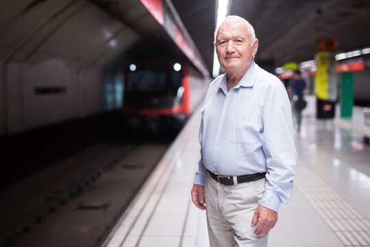 Mature European man standing in metro station and waiting for train arrival.