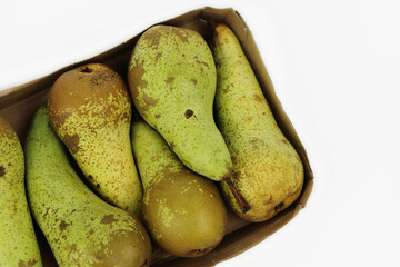 Pile of green ripe pears Conference packaged in rectangle carton cardboard container for retail sale, isolated on white background. Plastic free packaging. Top view. Selective focus.