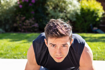 Young adult male doing a plank during an afternoon at-home workout on a yoga mat during the coronavirus pandemic.