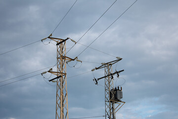 High-power electricity poles in the urban area connected to the smart grid. Power supply, power distribution, power transmission, high voltage concept photo. Cloudy sky. Malaga, Spain.
