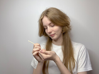 a young blonde girl gives herself a manicure