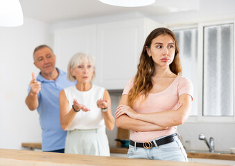 Upset adult daughter happens to reproach parents in the kitchen