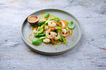 Green asparagus salad steamed as tips and slices with prawns and passion fruit vinaigrette served as a close-up on a Nordic Design plate with text space