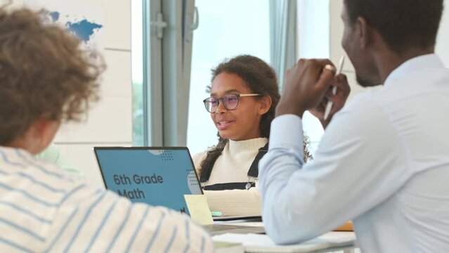 Waist up of multiracial 6th grade schoolchildren and their Black male teacher having discussion in class