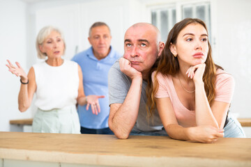 Fototapeta premium Husband and wife listen to their parents scold them in the home kitchen