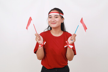 Fototapeta premium Cheerful young indonesian girl standing while holding red white flag. Isolated on white