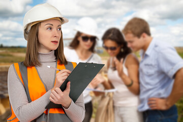 Woman builder. Consultation of customer for construction of house. Builder girl is holding clipboard. Architectural company specialist in helmet. Construction office worker. Selective focus
