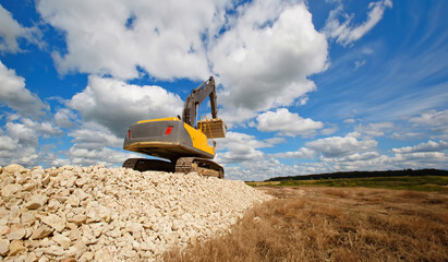 Excavator unload gravel. An excavator is paving a quarry road. - obrazy, fototapety, plakaty