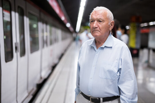 Senior man standing in subway station in front of train that just arrived.