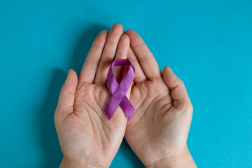 Eating disorders day. Female hands hold a purple ribbon on a blue background. Banner