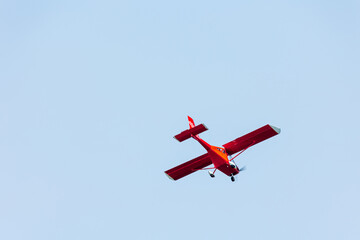 Bottom view of a red glider airplane flying and doing tricks over the blue air 