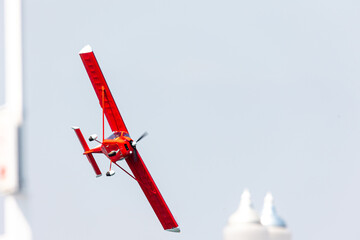 acrobatic red airplane glider flying fast over the blue air with motion blur at the propeller at...