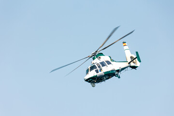 Close-up view of a Spanish military police helicopter doing tricks over the blue sky on a summer...