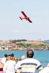 Gijon Air Show Festival in Asturias, with a seaplane flying low through San Lorenzo Beach with a lot of people enjoying its tricks 