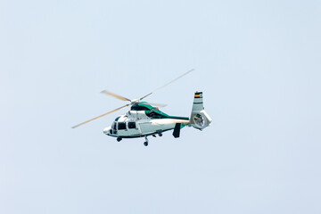 Fototapeta na wymiar white and green Spanish police helicopter flying in the sky at the Gijon Air show festival