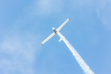 Top view of a gliders plane flying and doing tricks and stunts over the blue sky with white steam...