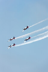 Planes squadron in arrow formation doing tricks and stunts over the blue sky with color wakes on a summer day at Gijon air show festival