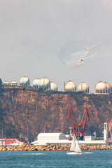 Gijon Air Show festival in Asturias, Spain, with a team of  two airplanes flying low through habor mountains with gas and hydrogen tanks and port cranes 